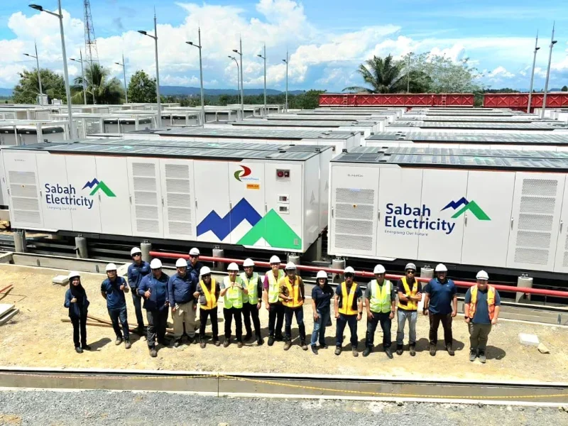 Rows of Sabah Electricity battery energy storage containers with the project team standing in front