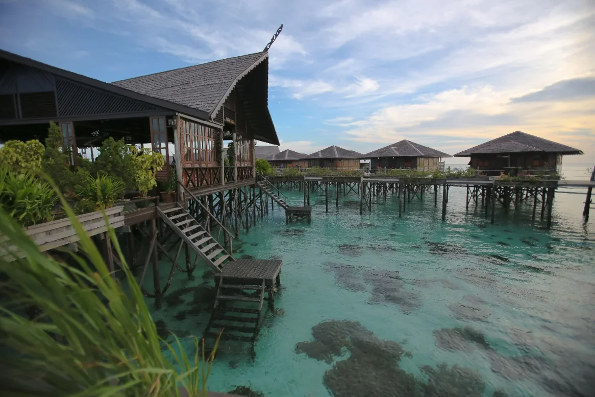Wooden water chalets on stilts at dusk off Semporna, the gateway town for Sipadan